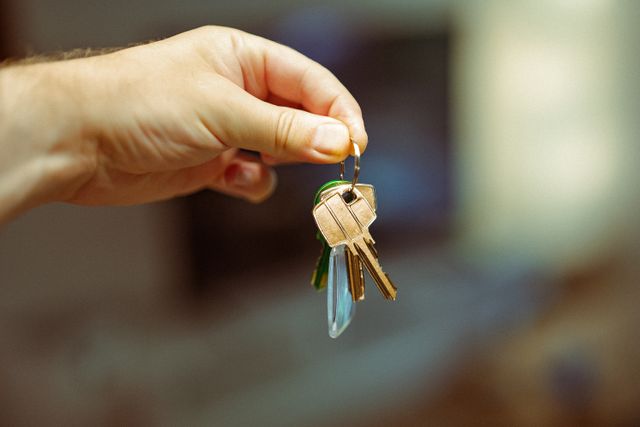 a hand holding a keyring with several house keys