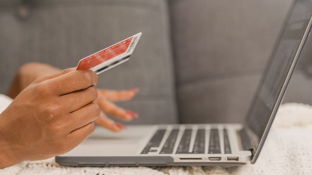 a person using a laptop while holding a credit card
