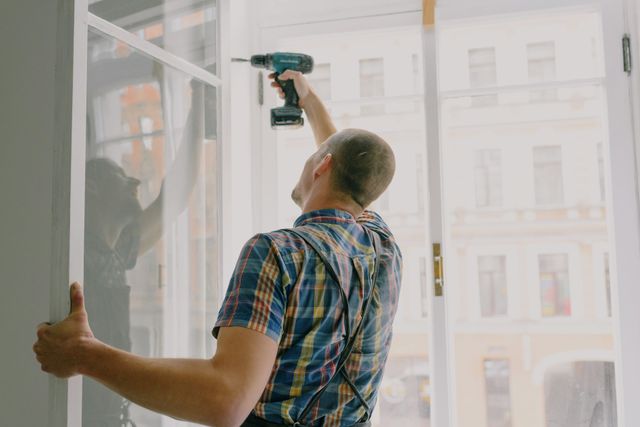 man installing a window with a power drill